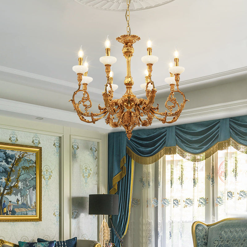 Classical brass chandelier installed in an elegant living room with patterned wallpaper and decor.