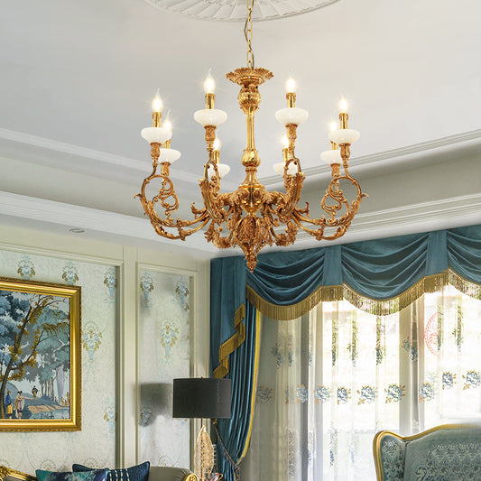 Classical brass chandelier installed in an elegant living room with patterned wallpaper and decor.