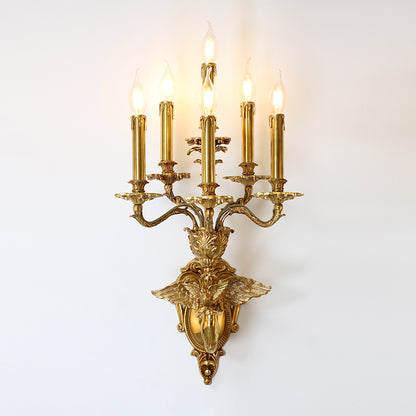 Side view of the ornate brass banquet wall lamp with angel and siren figures, mounted on a white wall.