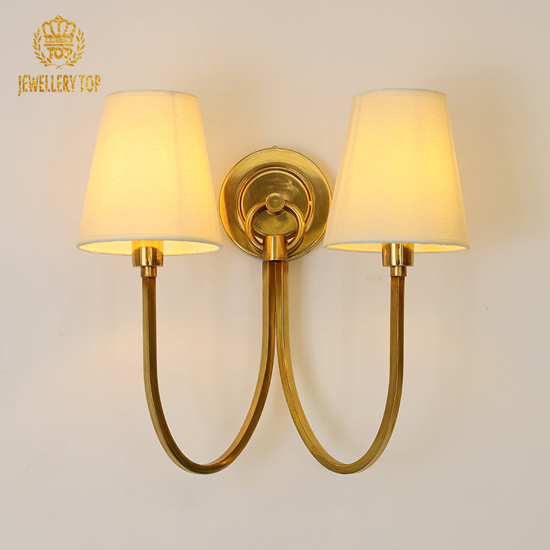 Front view of the JEWELLERY TOP Renaissance Doux brass wall lamp with two fabric shades on a white wall.