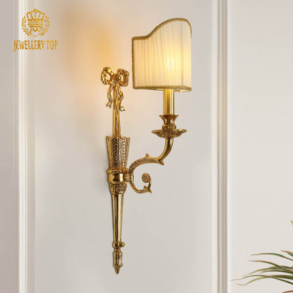 Front product view of the ornate golden sconce with a lit fabric lampshade, showcasing the JEWELLERY TOP brand logo.