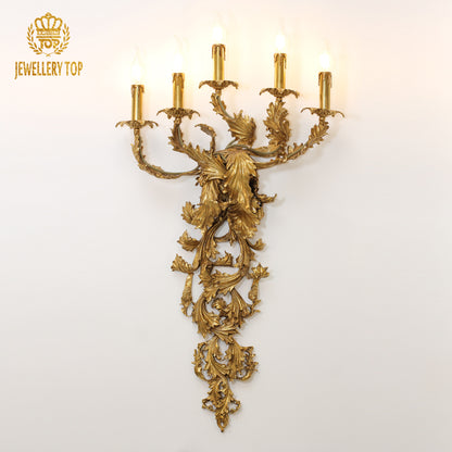 Front view of the golden Feuillage Royal brass wall sconce with leafy design and multiple candle bulbs on a white wall, brand JEWELLERY TOP.