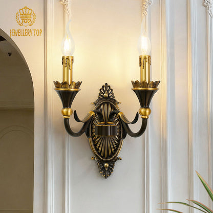 The French brass wall lamp with a dark central medallion and golden arms, installed beside an arched doorway.