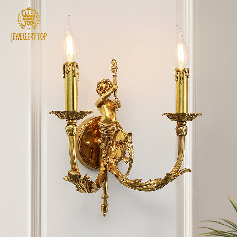 Close-up of the JEWELLERY TOP branded brass wall lamp, showcasing an angel holding a spear and ornate vine decorations.
