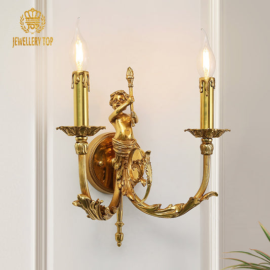 Close-up of the JEWELLERY TOP branded brass wall lamp, showcasing an angel holding a spear and ornate vine decorations.