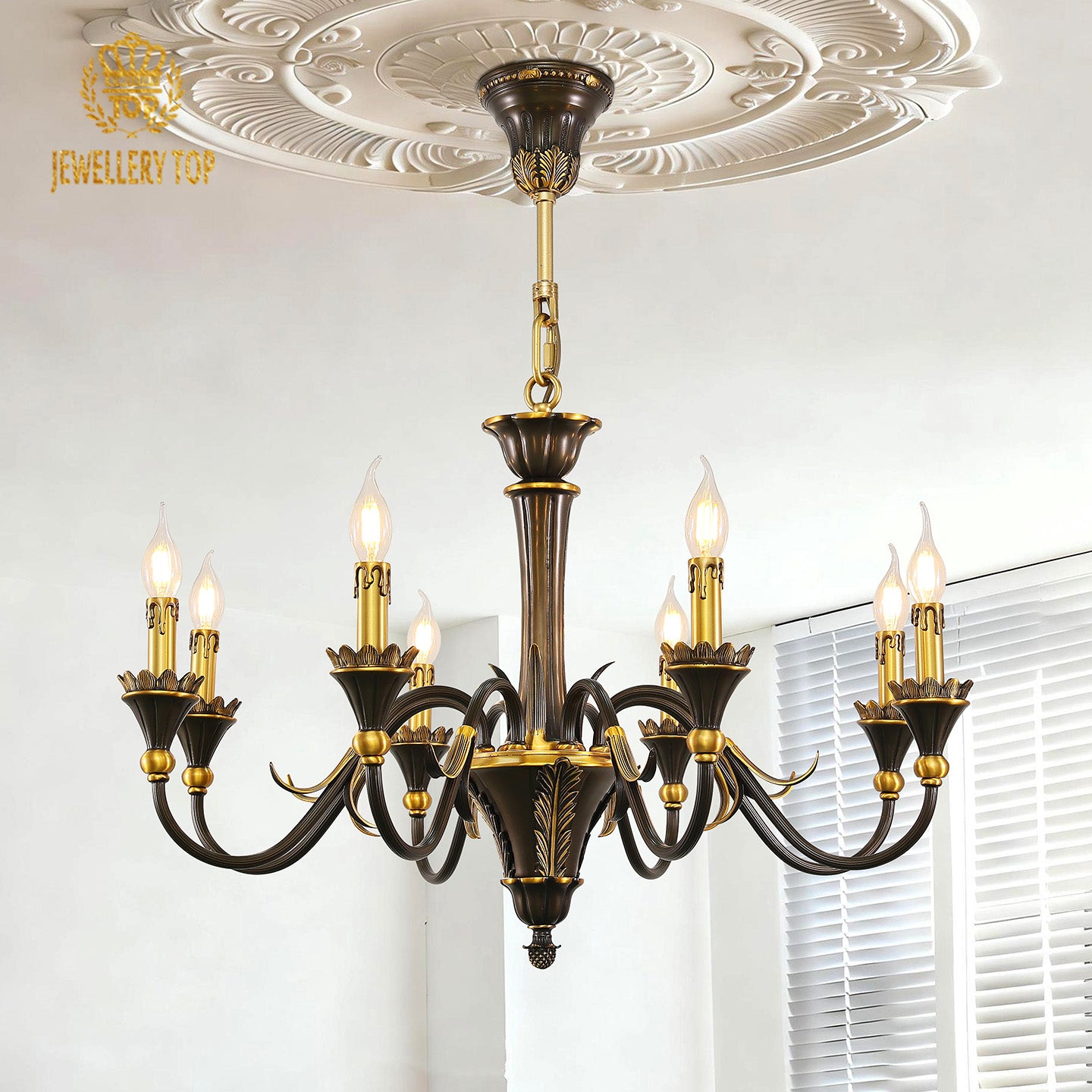 An eight-arm vintage brass chandelier lit under an ornate white ceiling, JEWELLERY TOP.