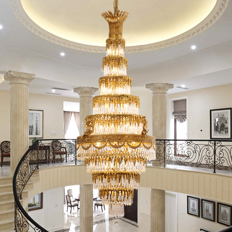 The brass chandelier installed in a grand staircase hall with Roman columns and artwork.