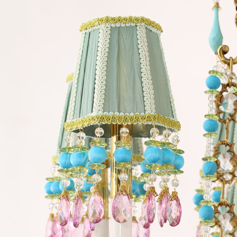 Extreme detail of a light teal fabric lampshade with white trim and layered crystal pendants.