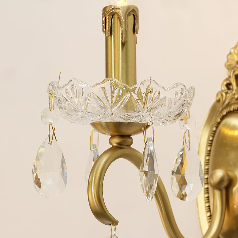 Extreme close-up of a crystal petal tray and hanging droplets on the brass arm of the decorative lamp.