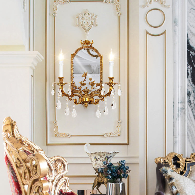 The luxury decorative wall lamp installed on a white paneled wall, illuminating a classic interior with a blue floral vase.