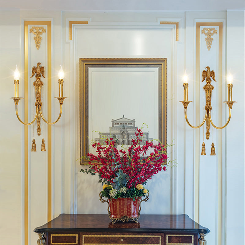 A pair of the golden eagle wall lamps installed symmetrically on a white and gold-accented wall with a central painting.