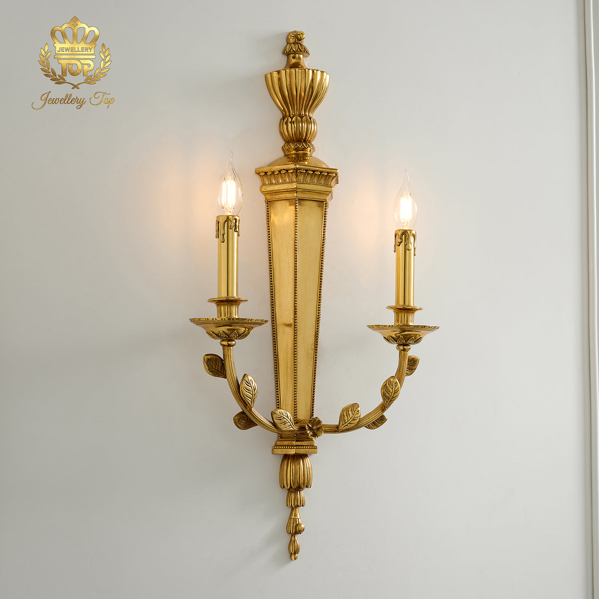 Angle view of the illuminated George III Girandole brass candle sconce against a white wall by Jewellery Top