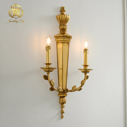 Angle view of the illuminated George III Girandole brass candle sconce against a white wall by Jewellery Top