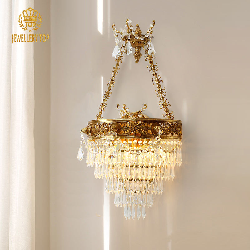 Versailles Cascade golden brass wall sconce with a multi-tiered crystal shade, JEWELLERY TOP branding visible on white wall.
