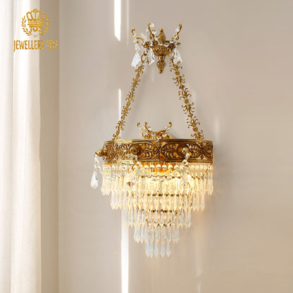 Versailles Cascade golden brass wall sconce with a multi-tiered crystal shade, JEWELLERY TOP branding visible on white wall.