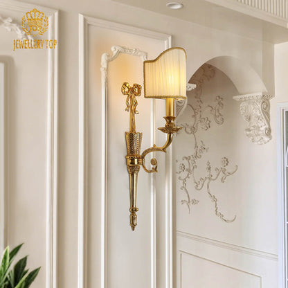 The home decor wall light mounted on a white textured wall with intricate molding, emitting a soft, warm glow.
