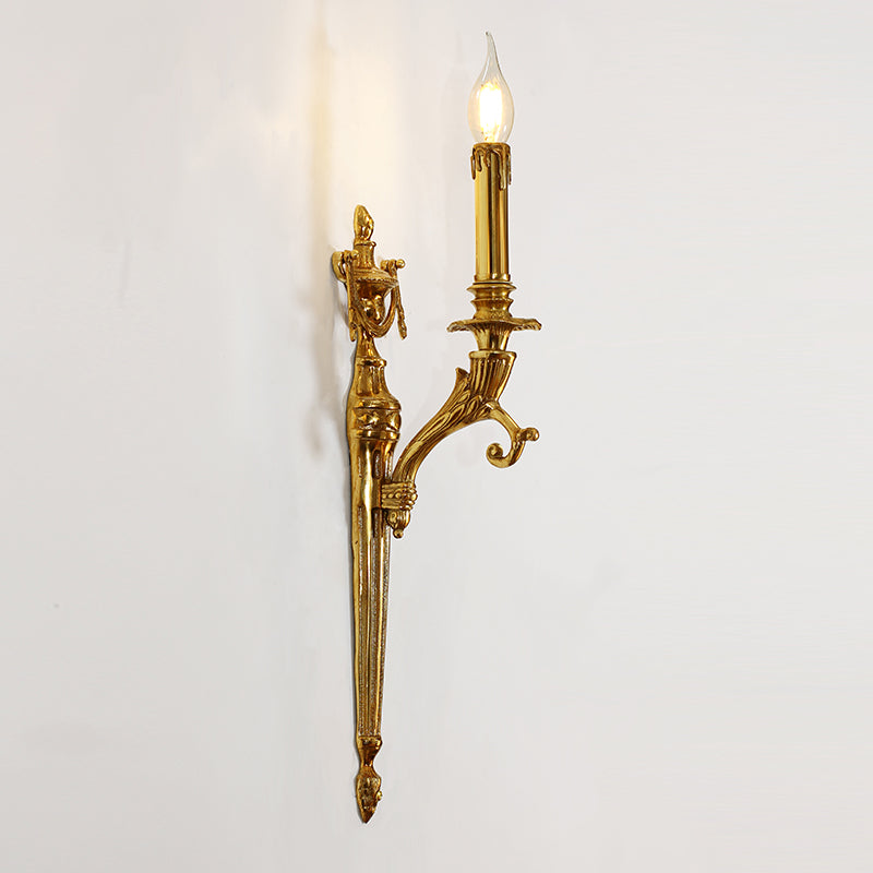 Close-up detail of the ornate golden wall sconce, highlighting its curved arm, candle bulb, and intricate scrollwork.