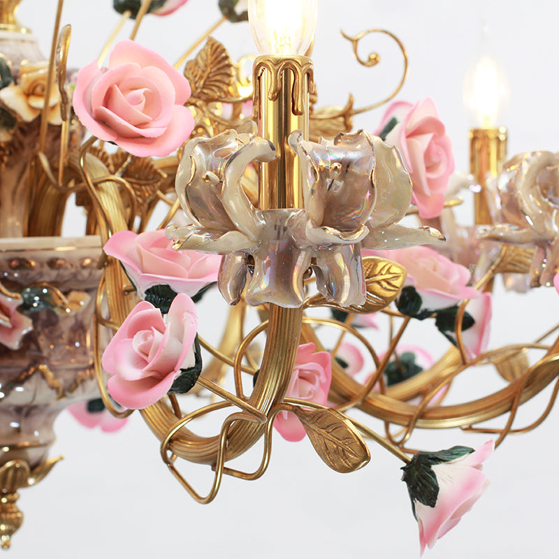 Extreme detail shot of hand-painted ceramic roses and brass leaves on a decorative chandelier.