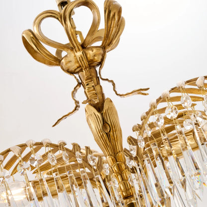 Close-up detail of brass palm frond arm and hanging crystal droplets on a luxury chandelier.