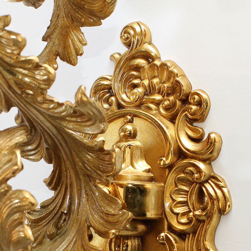 Extreme close-up of the Rococo-style engraved patterns and polished finish on the golden wall lamp.