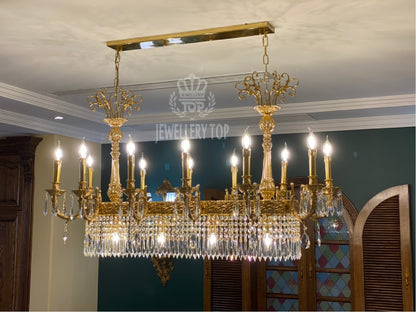 Branded brass crystal chandelier (JEWELLERY TOP) against a teal and wood-paneled wall.