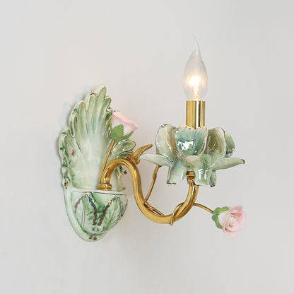 Extreme close-up of a blush pink porcelain rose and gilded leaf accent on the luxury sconce.