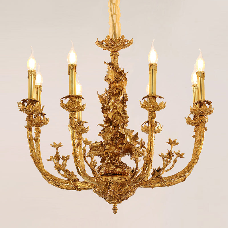 A lit decorative brass chandelier with curved arms and ceramic flower accents, isolated on white.