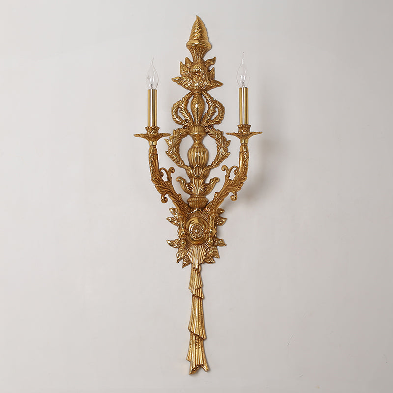 Isolated macro photography of the sconce’s incredibly detailed backplate with floral baskets, leaves, and a sunburst medallion.