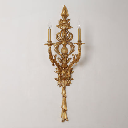 Isolated macro photography of the sconce’s incredibly detailed backplate with floral baskets, leaves, and a sunburst medallion.