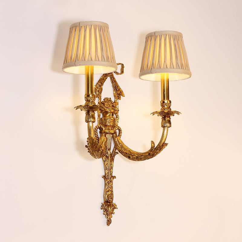 The European-style wall sconce with detailed metalwork and soft glow, mounted beside an ornate gold-framed mirror.