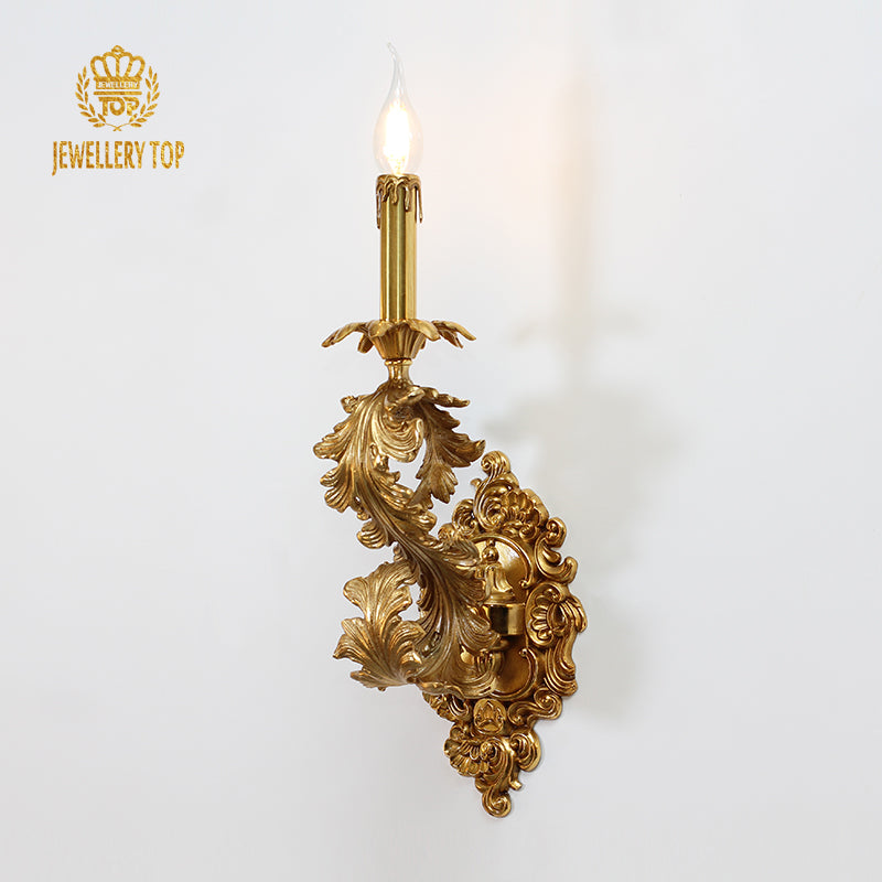 JEWELLERY TOP branded close-up of the ornate single-head candle wall light with glowing bulb.