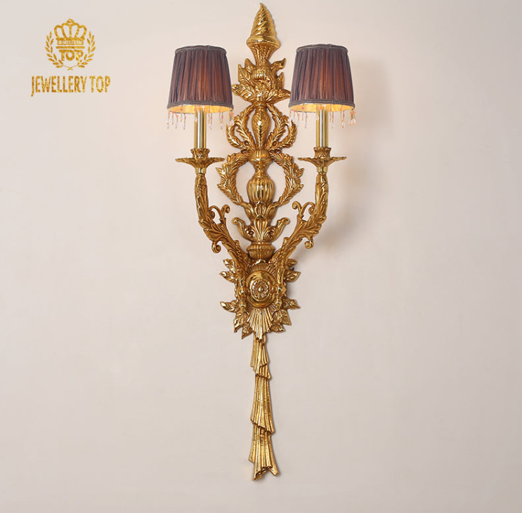 JEWELLERY TOP branded French wall sconce with deep purple lampshades, ornate crest, and lit candle bulbs.