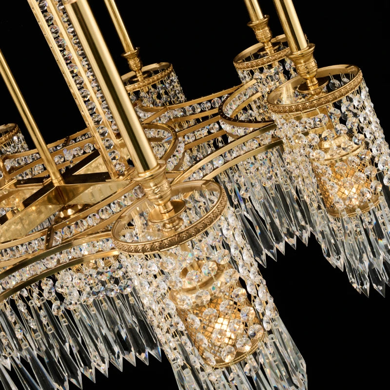 Close-up detail of ornate golden brass arms and hanging crystal strands, luxury decorative chandelier.