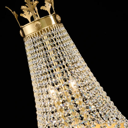 Extreme close-up of the ornate crown-shaped brass top with sunburst emblems on a crystal chandelier.