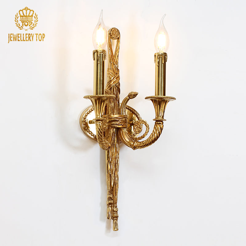 The French antique wall sconce installed on a white wall with gold trim, emitting a warm glow beside artwork and flowers.