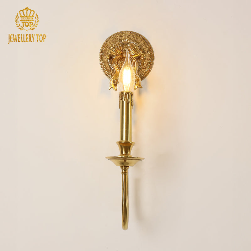 Detailed macro close-up of the brass wall lamp’s floral engraved backplate and beaded edge decoration.