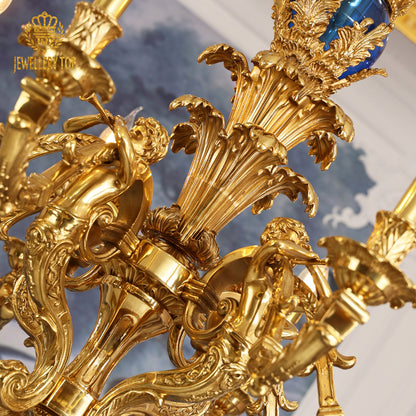 Close-up detail of a cherub and floral brass carving on the antique chandelier.
