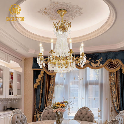 The crystal decorative brass chandelier above a dining table with flowers and grey chairs.