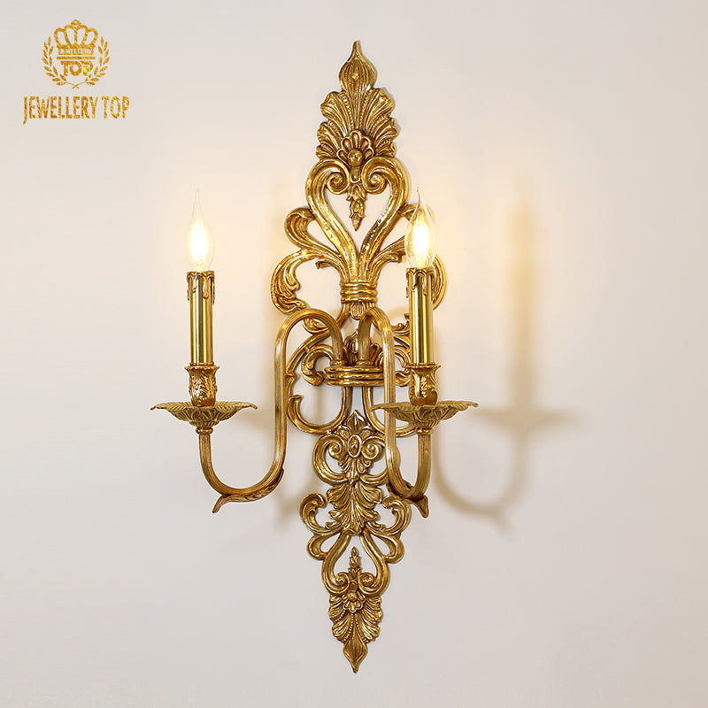 JEWELLERY TOP branded close-up of the ornate designer wall lamp, showcasing its symmetrical arms and lit bulbs.