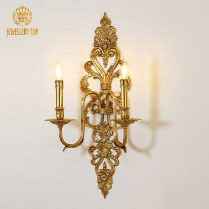 JEWELLERY TOP branded close-up of the ornate designer wall lamp, showcasing its symmetrical arms and lit bulbs.