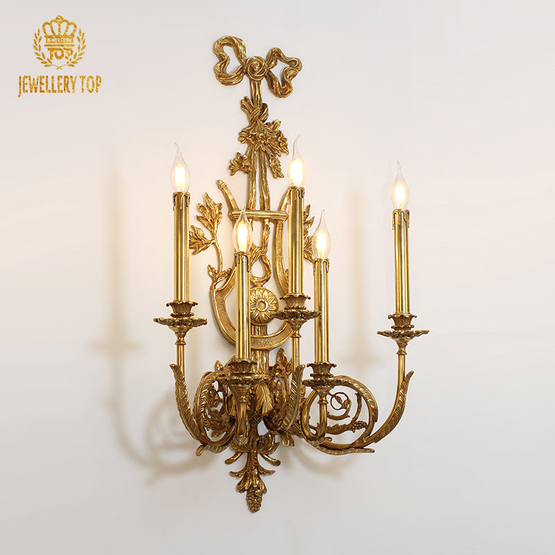 Front product view of the golden five-light brass candelabra sconce with intricate floral and leaf carvings.