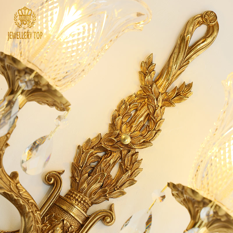 Macro detail focusing on the intricate brass scrollwork, textured patina, and a single sparkling crystal pendant.