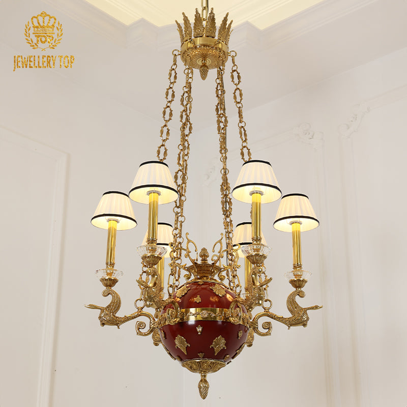 Front view of the JEWELLERY TOP brass chandelier with red center and white pleated shades.