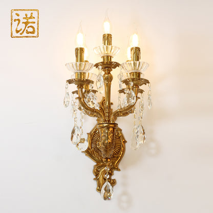 Close-up of the antique bronze wall lamp with three candle bulbs and a seal hallmark.
