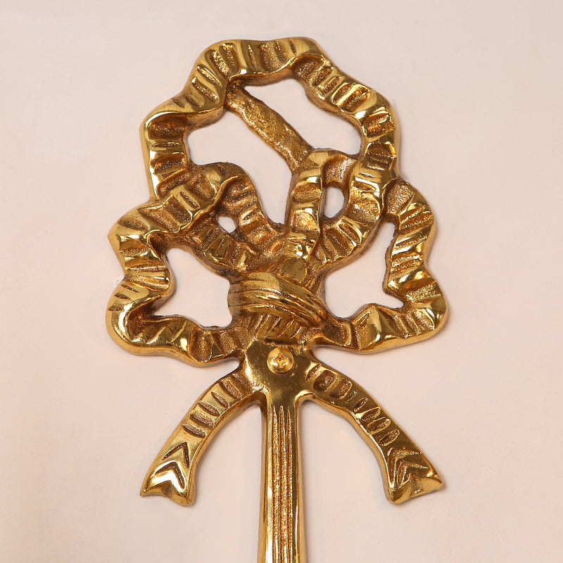 Macro detail of the ornate twisted metal knot and scrollwork component of the golden brass wall lamp.