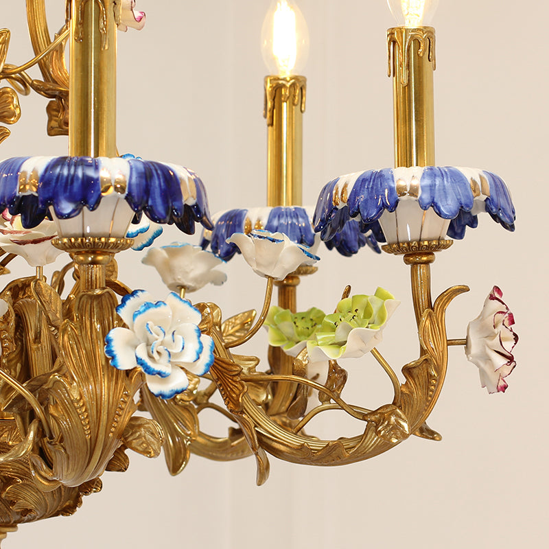 Detailed side view of the chandelier's brass arms, ceramic flowers, and glowing candle lights.