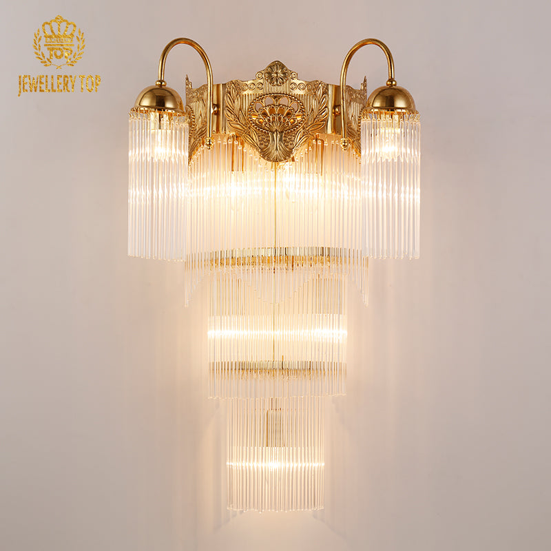 JEWELLERY TOP branded product shot of the ornate brass sconce with lit bulbs and crystal details.