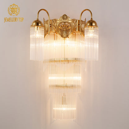 JEWELLERY TOP branded product shot of the ornate brass sconce with lit bulbs and crystal details.