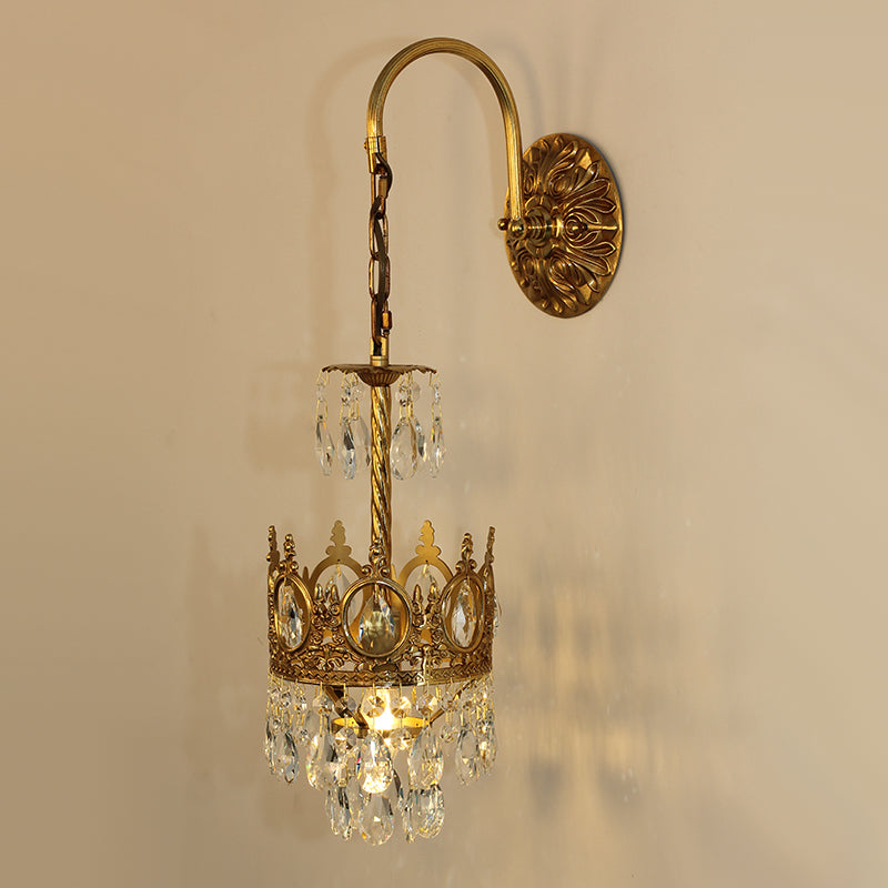 Close-up detail of the ornate brass scrollwork and faceted crystal strands on the luxury bedside wall lamp.