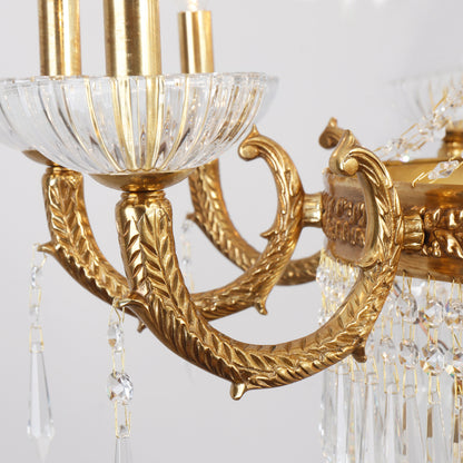 Macro detail of engraved brass acanthus leaf, a fluted glass shade, and crystal chains.